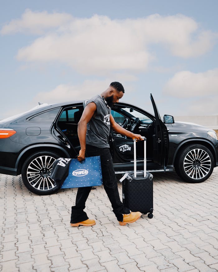 Man unloading luggage from luxury car outdoors on a sunny day.