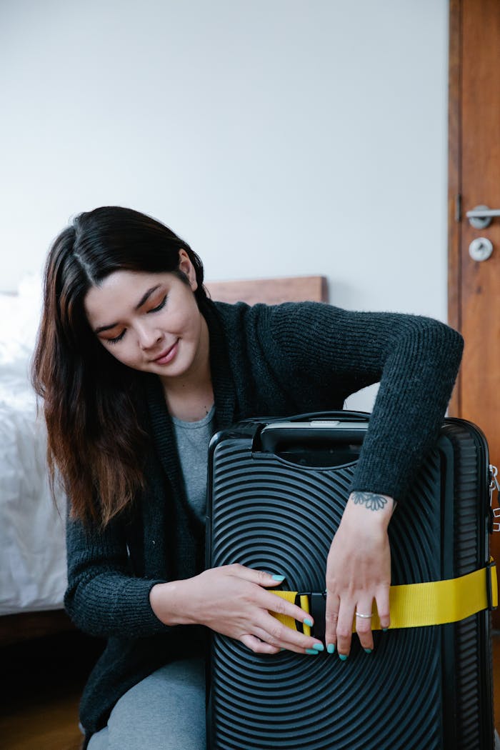 Young woman packing a stylish suitcase in a cozy bedroom, preparing for travel adventure.